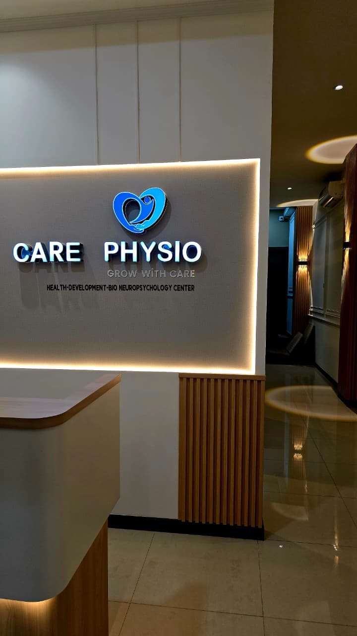 Resepsi klinik Care Physio Paskal 23 dengan logo menyala di dinding kayu